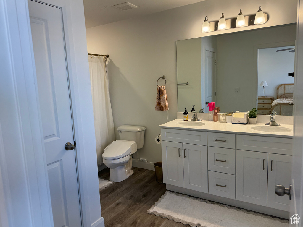 Bathroom featuring wood-type flooring, toilet, and double sink vanity