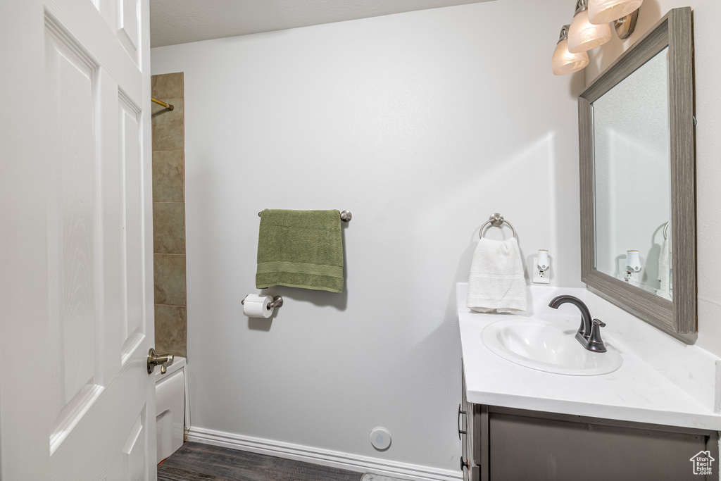 Bathroom with tiled shower / bath combo, hardwood / wood-style floors, and vanity