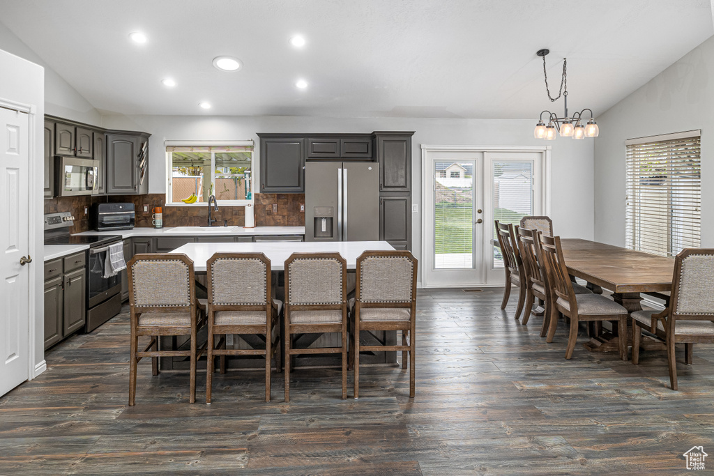 Kitchen with a center island, tasteful backsplash, stainless steel appliances, dark hardwood / wood-style floors, and vaulted ceiling