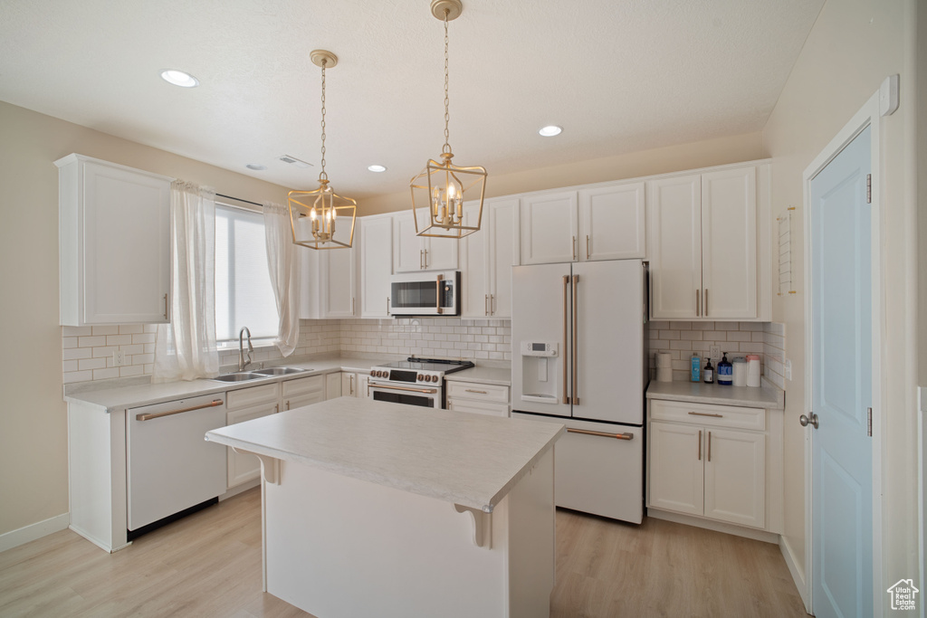 Kitchen featuring a kitchen island, light hardwood / wood-style floors, white appliances, and sink