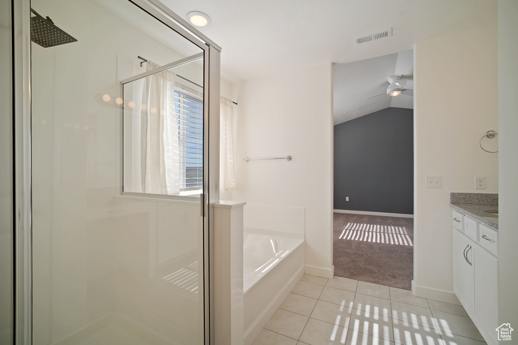Bathroom with ceiling fan, vaulted ceiling, tile flooring, vanity, and separate shower and tub