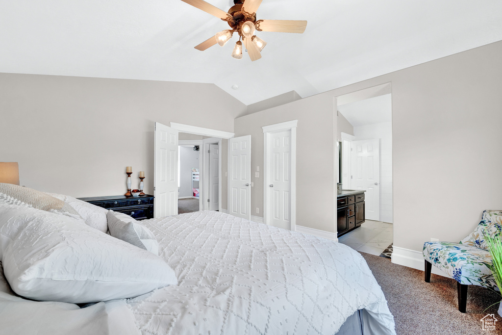 Bedroom with vaulted ceiling, ceiling fan, light carpet, and connected bathroom