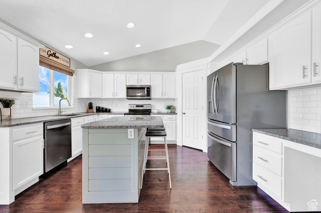 Kitchen featuring a kitchen island, dark hardwood / wood-style floors, tasteful backsplash, and stainless steel appliances