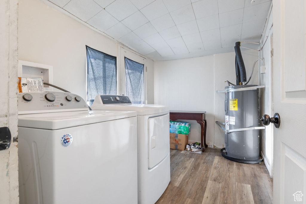 Laundry area featuring strapped water heater, hardwood / wood-style flooring, and washer and clothes dryer