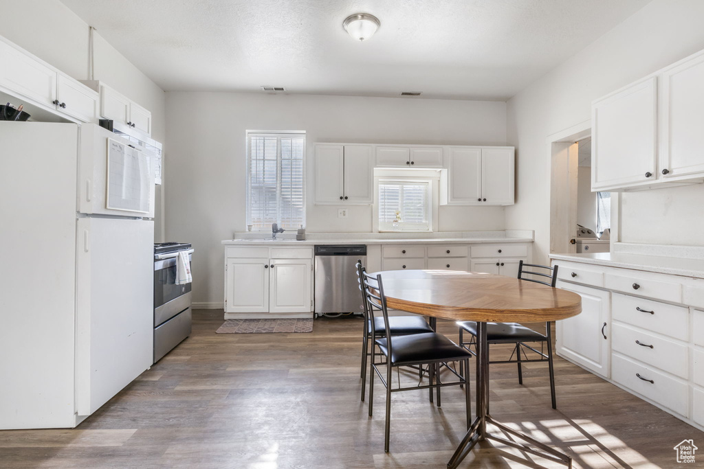 Kitchen featuring range, white cabinetry, white fridge, hardwood / wood-style flooring, and dishwasher