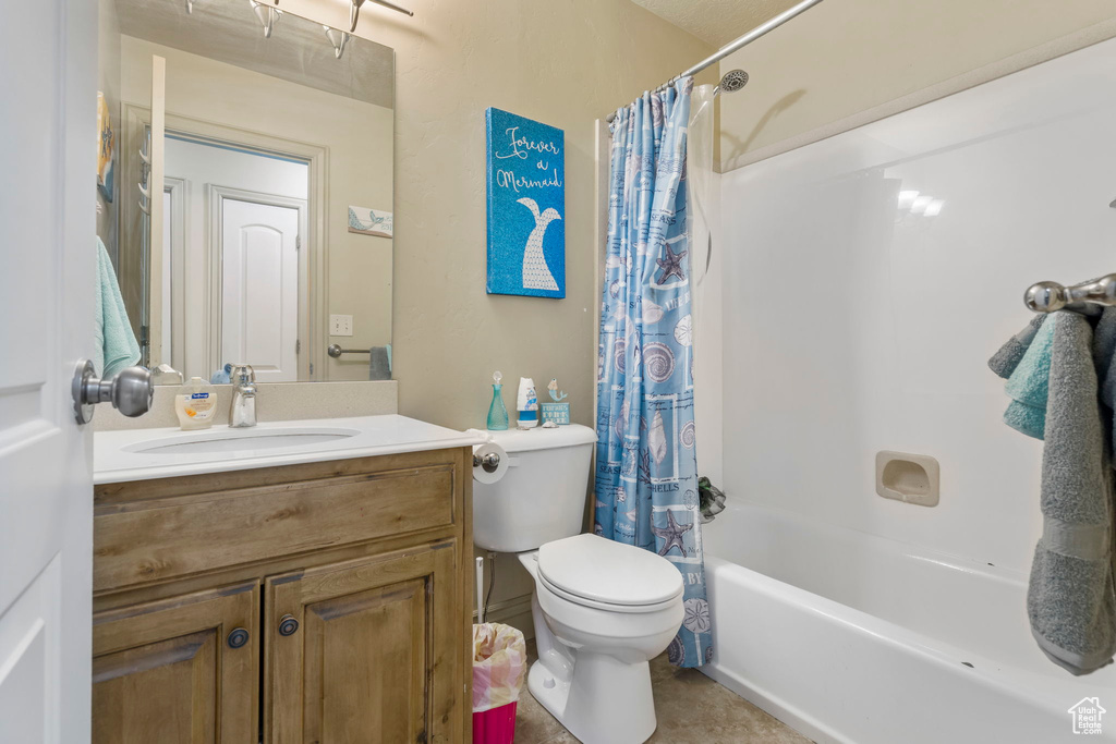 Full bathroom featuring tile flooring, large vanity, toilet, and shower / bath combo with shower curtain