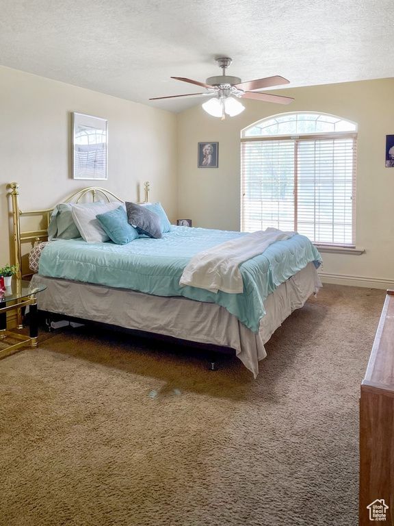 Bedroom with ceiling fan, carpet floors, and a textured ceiling
