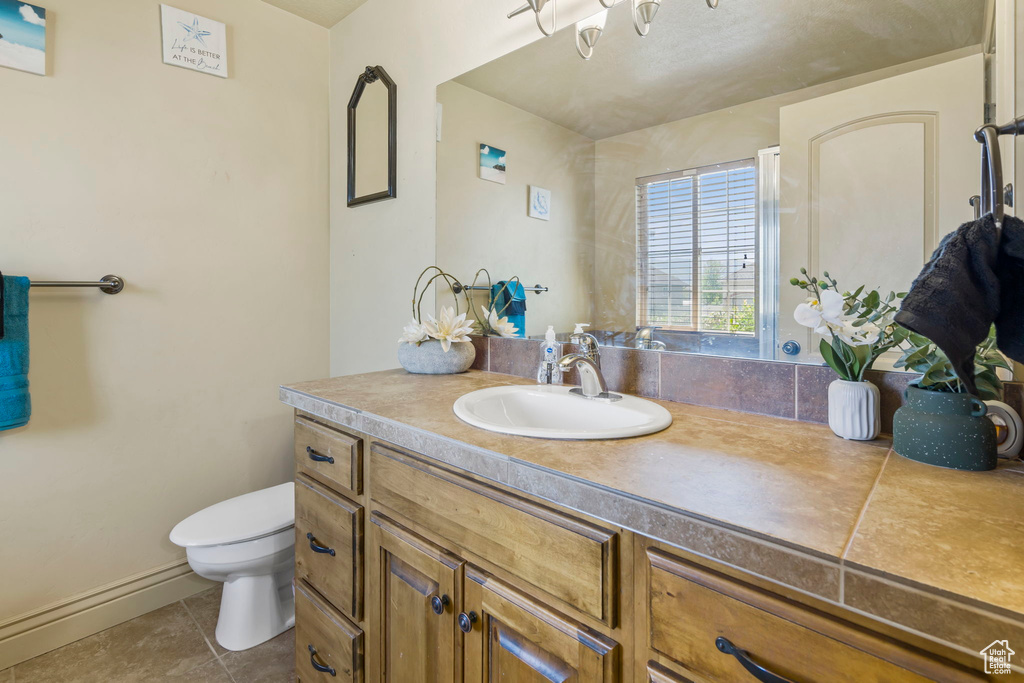 Bathroom featuring toilet, vanity with extensive cabinet space, and tile flooring