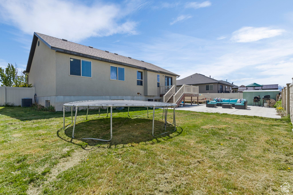 View of yard featuring a trampoline, a patio area, an outdoor hangout area, and central AC