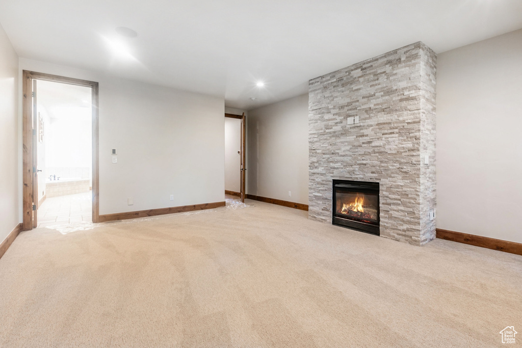 Unfurnished living room with a fireplace and light carpet