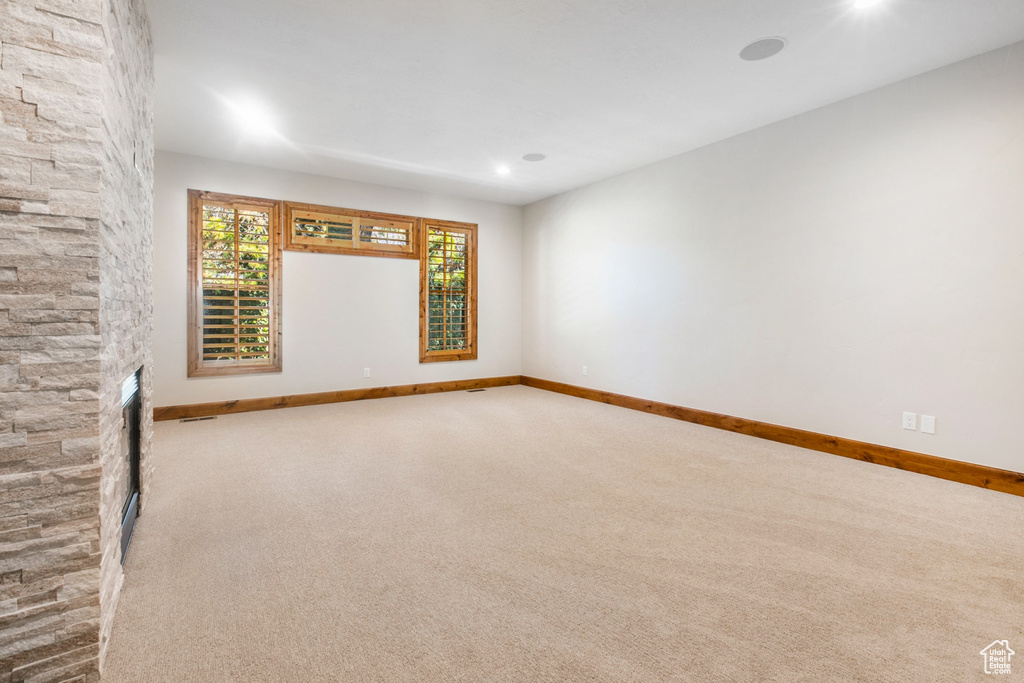 Spare room with a stone fireplace and light carpet