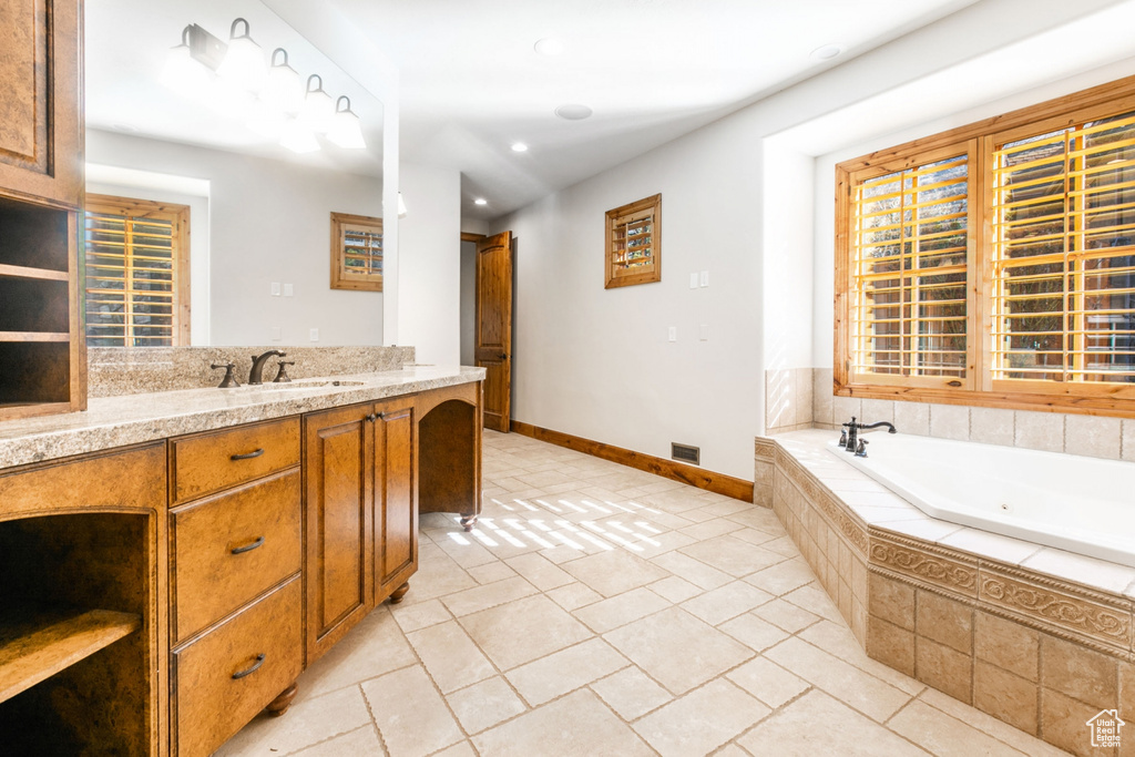 Bathroom with tiled bath, tile flooring, and vanity