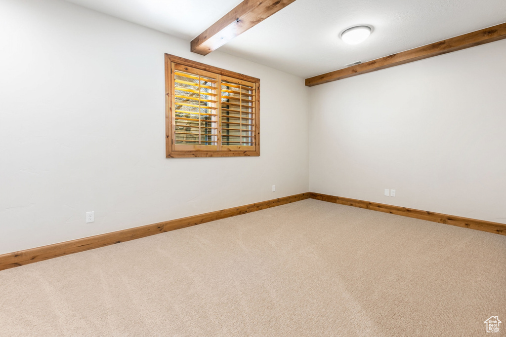 Unfurnished room with beam ceiling and carpet floors