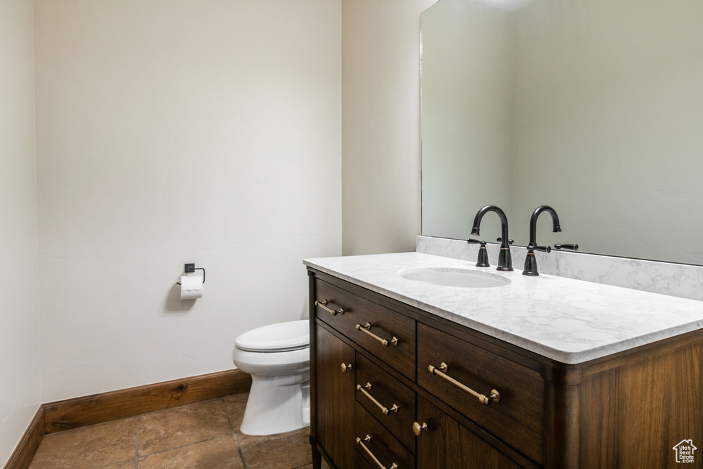 Bathroom with toilet, vanity, and tile floors