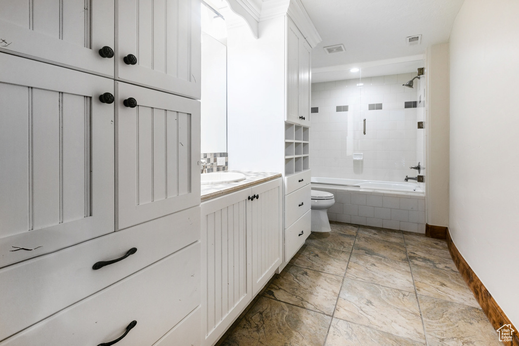 Full bathroom featuring tile floors, toilet, vanity, and tiled shower / bath