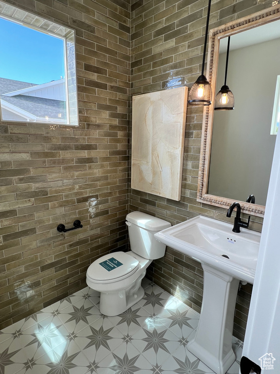 Bathroom featuring tile walls, sink, toilet, and tile flooring