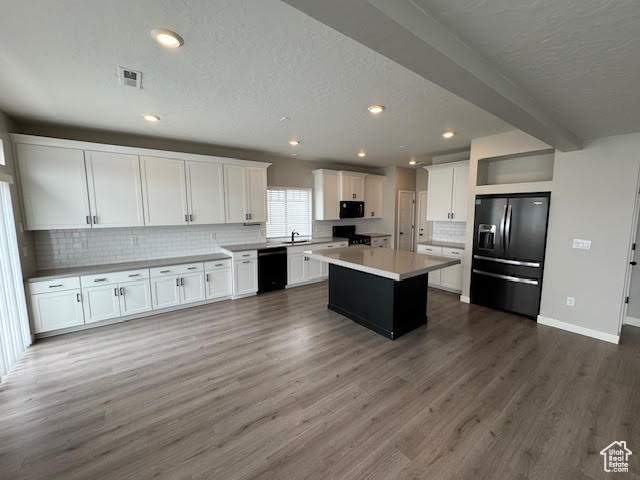 Kitchen with white cabinets, dark hardwood / wood-style floors, a kitchen island, and black appliances