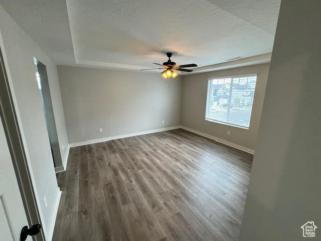 Empty room featuring dark hardwood / wood-style flooring, ceiling fan, and a textured ceiling