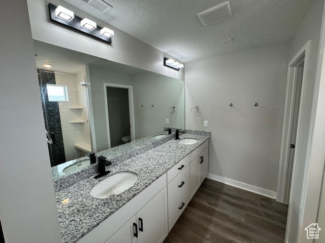 Bathroom featuring wood-type flooring, toilet, and dual bowl vanity
