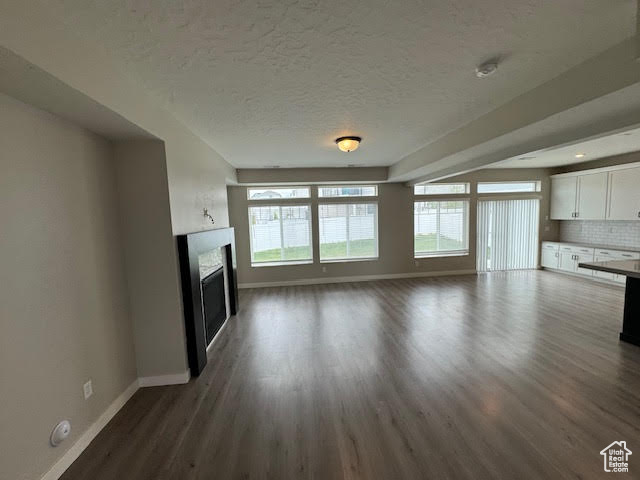 Unfurnished living room with dark hardwood / wood-style floors and a textured ceiling