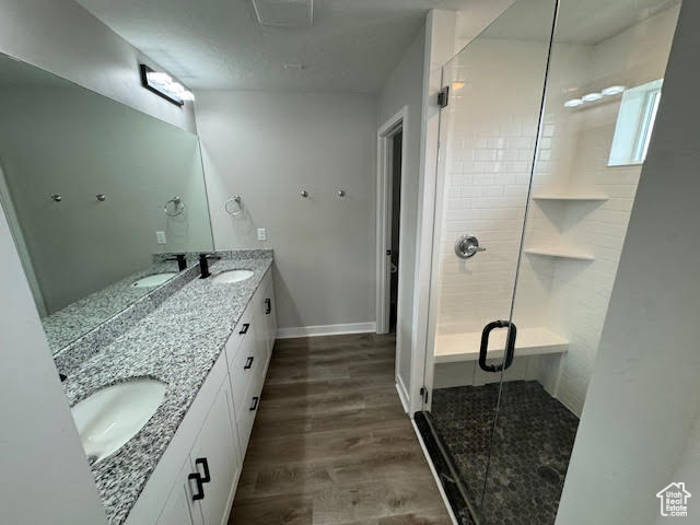 Bathroom with a shower with shower door, hardwood / wood-style flooring, and double sink vanity