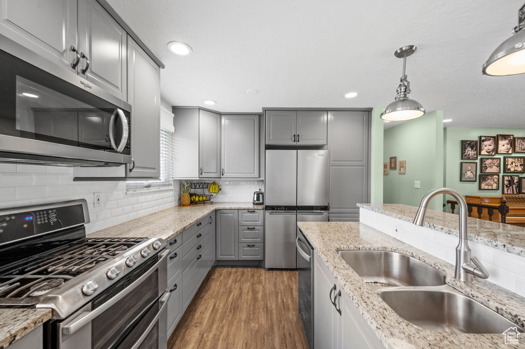 Kitchen featuring appliances with stainless steel finishes, gray cabinetry, hardwood / wood-style flooring, and sink