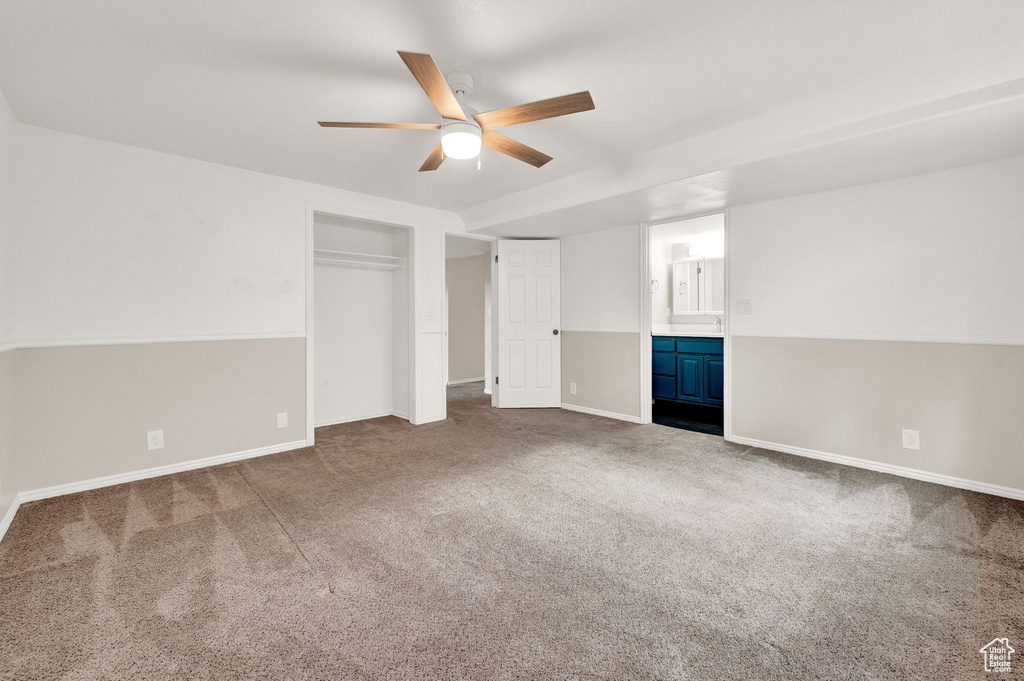 Empty room with ceiling fan and dark carpet