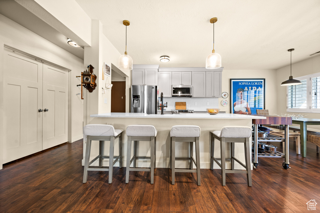 Kitchen featuring a kitchen breakfast bar, dark hardwood / wood-style flooring, stainless steel appliances, and decorative light fixtures
