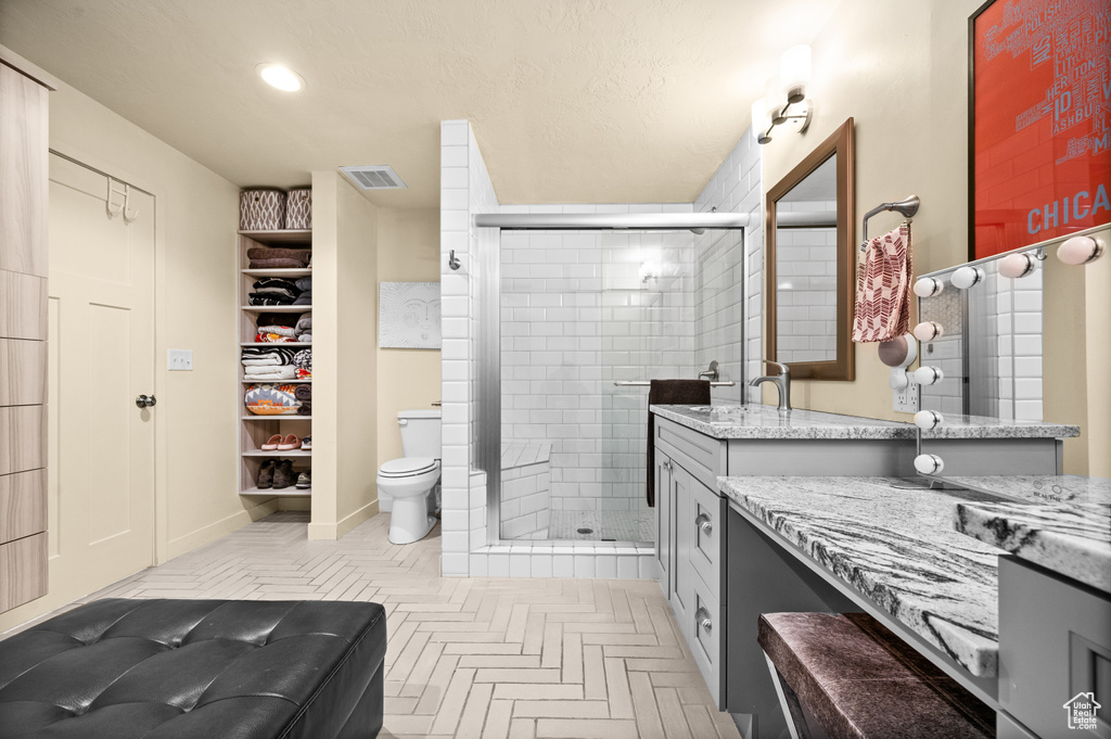 Bathroom featuring walk in shower, vanity, and toilet