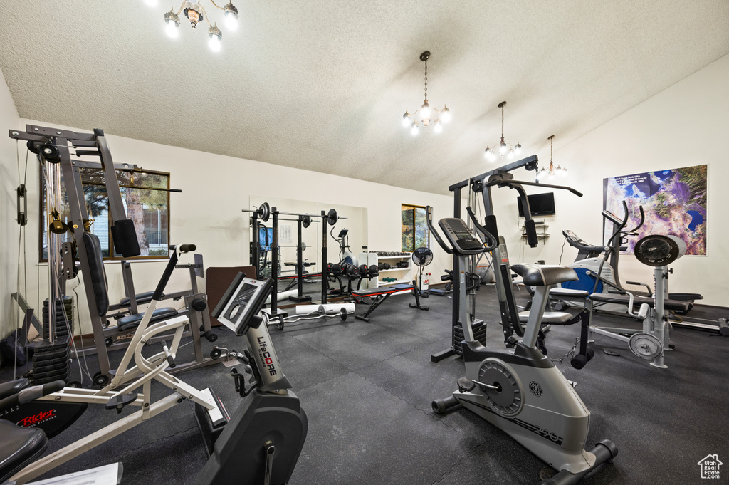 Workout area with a notable chandelier, a textured ceiling, and lofted ceiling
