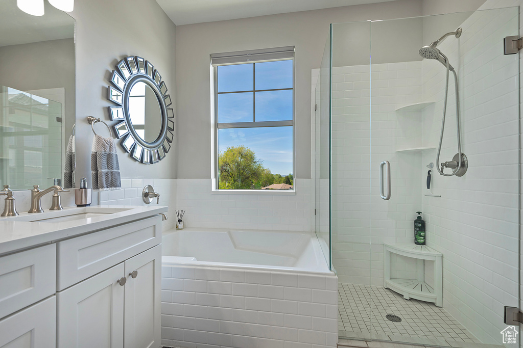 Bathroom featuring tile walls, large vanity, independent shower and bath, and tile floors