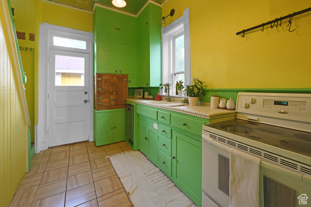 Kitchen featuring sink, light tile floors, white range with electric cooktop, and green cabinets