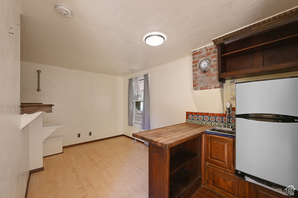 Kitchen featuring hardwood / wood-style floors, sink, brick wall, and white fridge