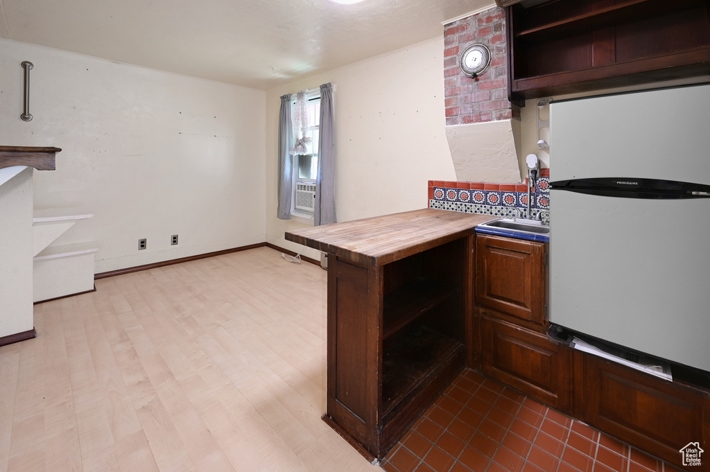Kitchen with white refrigerator, wood-type flooring, butcher block counters, and sink