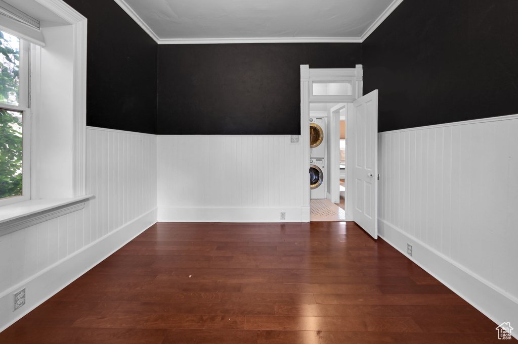 Spare room with ornamental molding, dark hardwood / wood-style floors, and stacked washer and clothes dryer