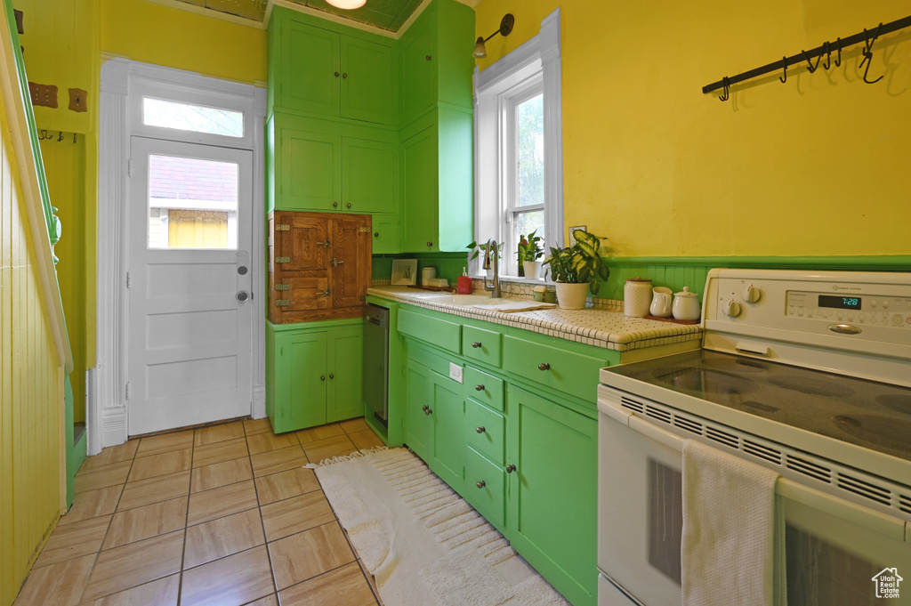Kitchen featuring light tile floors, sink, dishwasher, white range oven, and green cabinetry