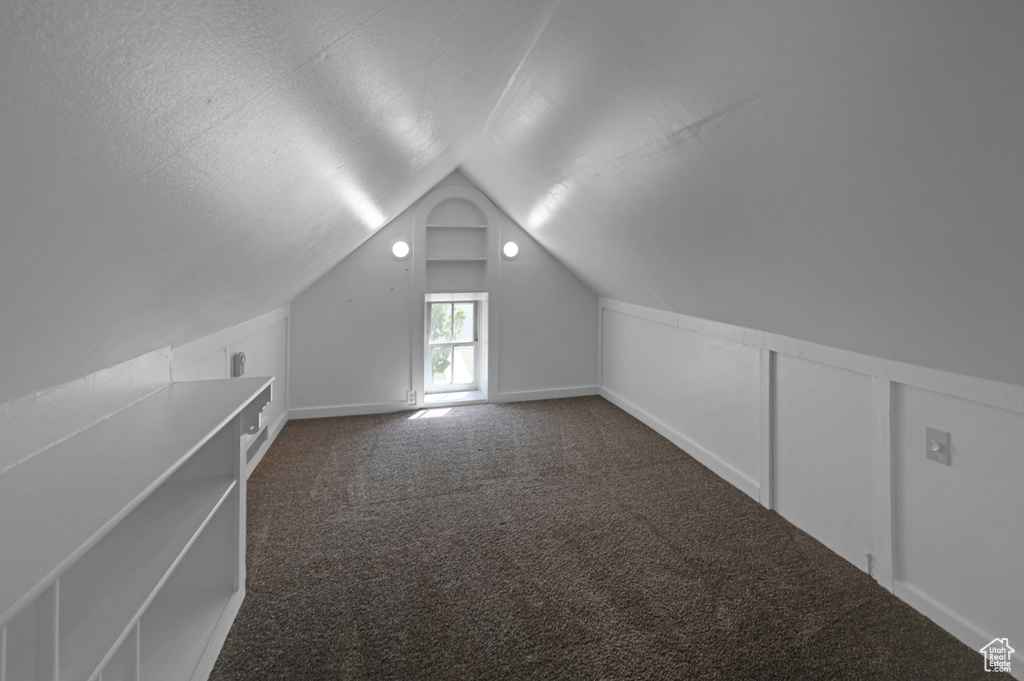 Additional living space with lofted ceiling, carpet floors, and a textured ceiling
