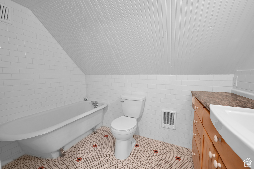 Bathroom featuring tile flooring, tile walls, toilet, vaulted ceiling, and vanity