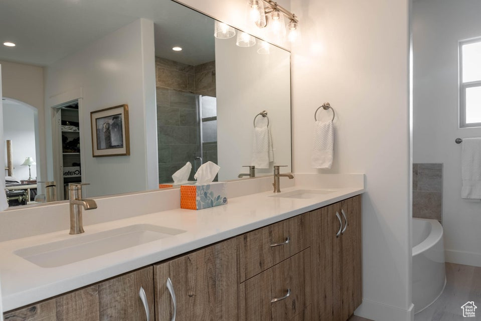 Bathroom featuring dual bowl vanity, separate shower and tub, and hardwood / wood-style floors