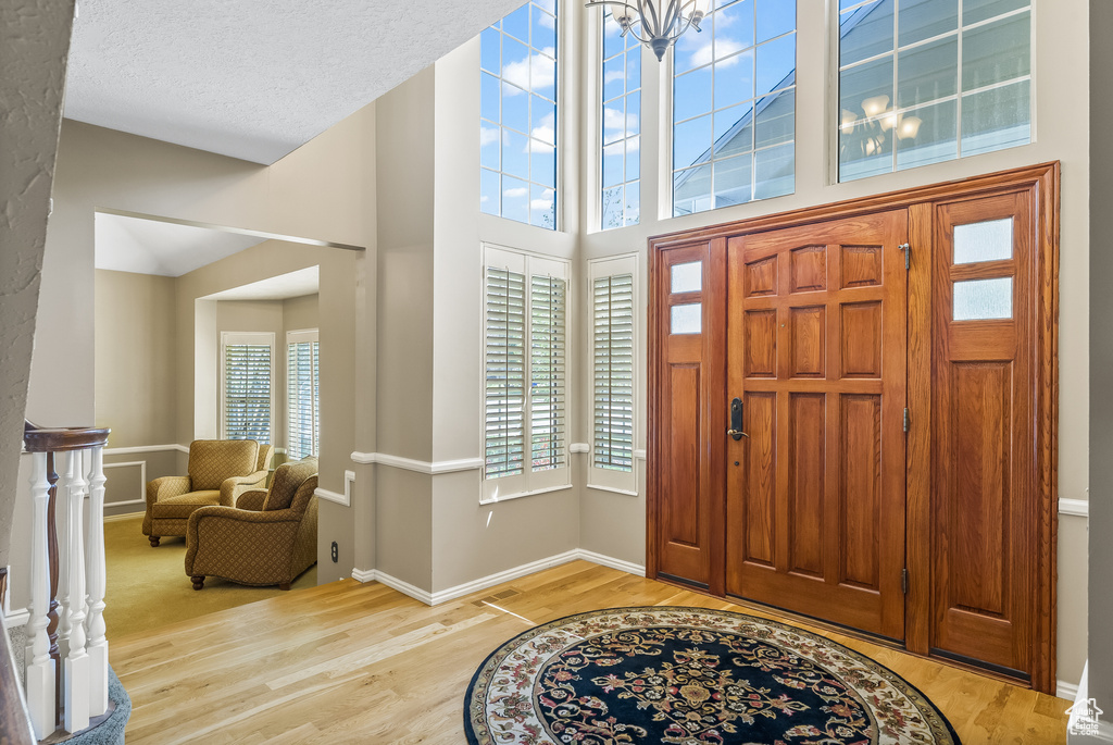 Entryway featuring light hardwood / wood-style floors, a high ceiling, and a textured ceiling