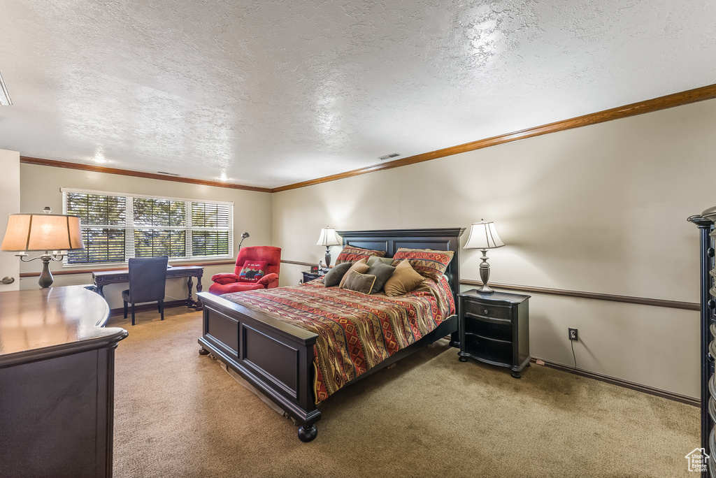 Bedroom featuring carpet, crown molding, and a textured ceiling