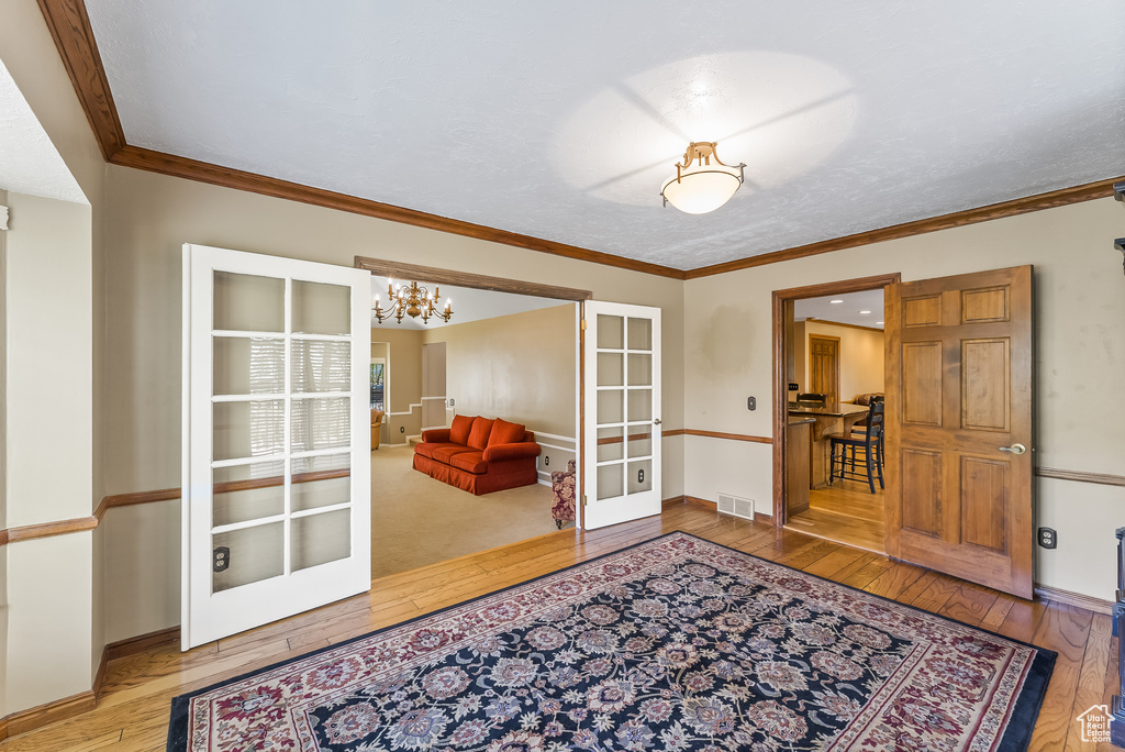 Sitting room with wood-type flooring, french doors, and crown molding