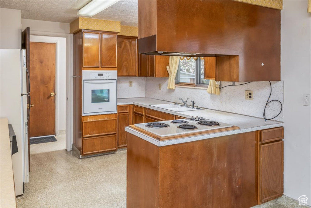 Kitchen with sink, white appliances, tasteful backsplash, and a textured ceiling