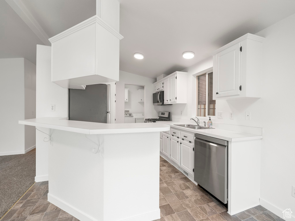 Kitchen featuring light colored carpet, appliances with stainless steel finishes, washer and dryer, and white cabinets