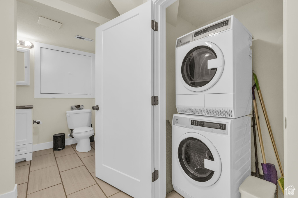 Laundry room featuring light tile flooring and stacked washer / drying machine