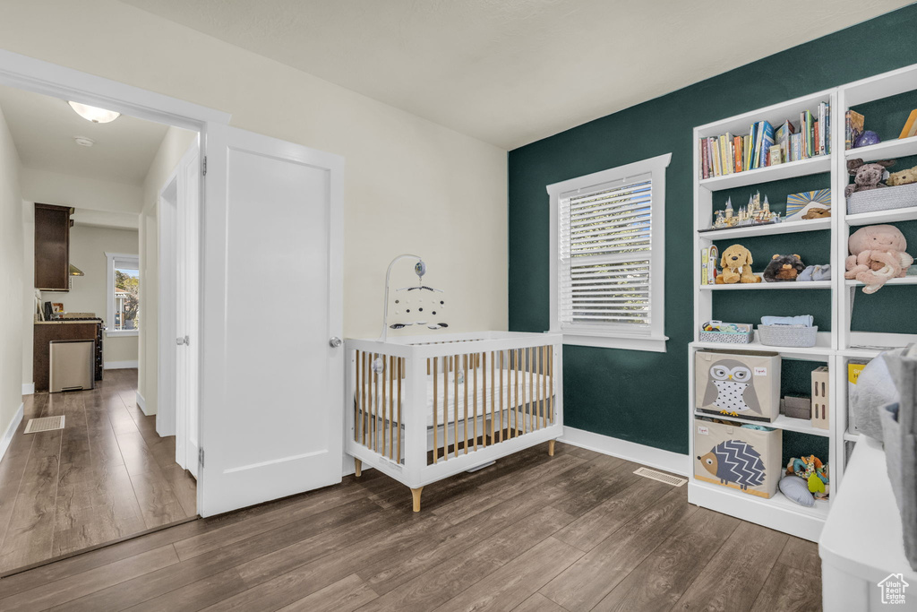 Bedroom featuring dark wood-type flooring and a crib