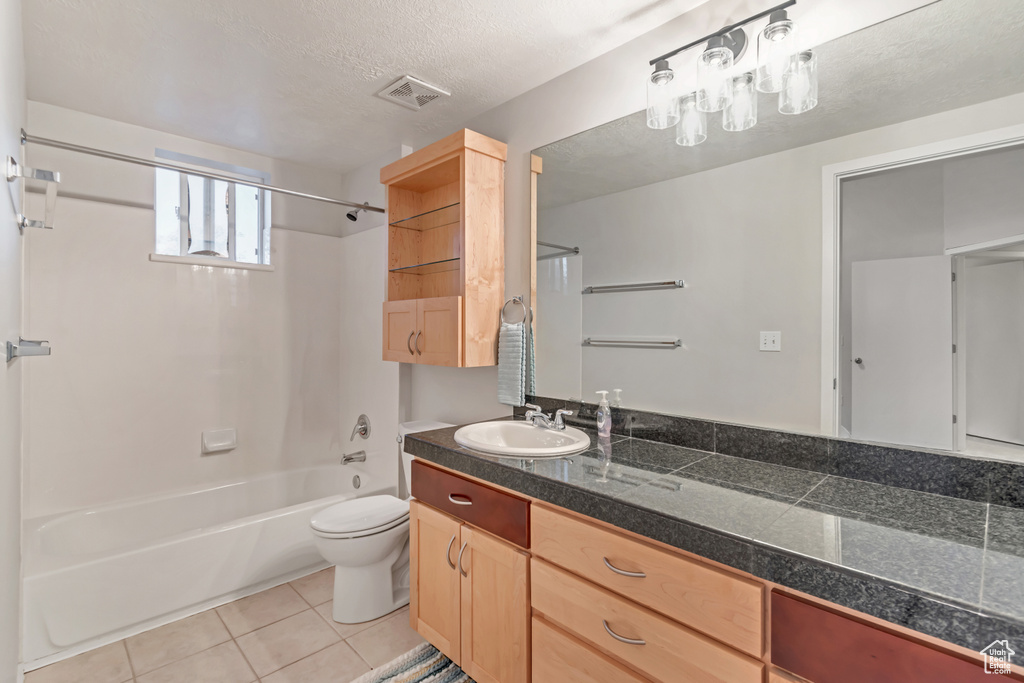 Full bathroom featuring vanity with extensive cabinet space, shower / tub combination, tile floors, toilet, and a textured ceiling