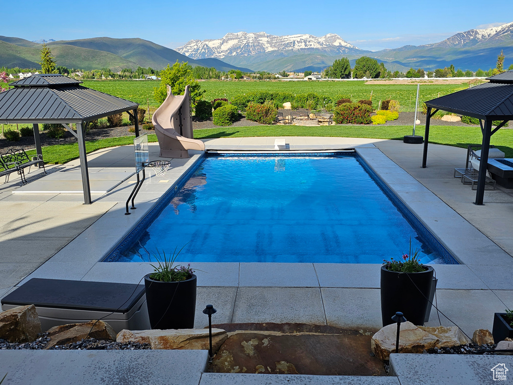 View of swimming pool with a patio area, a mountain view, and a water slide