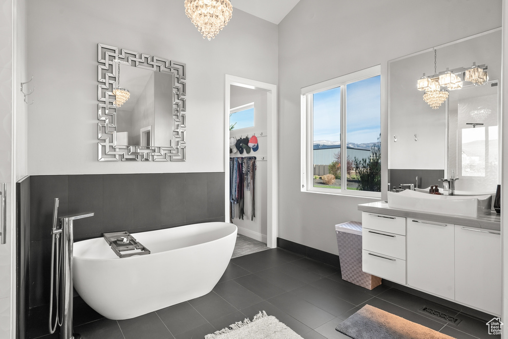 Bathroom featuring a bathing tub, tile flooring, a notable chandelier, and large vanity