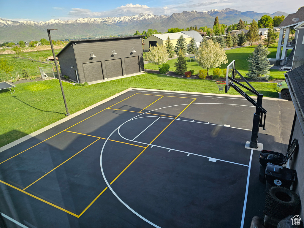 View of sport court with a mountain view and a yard